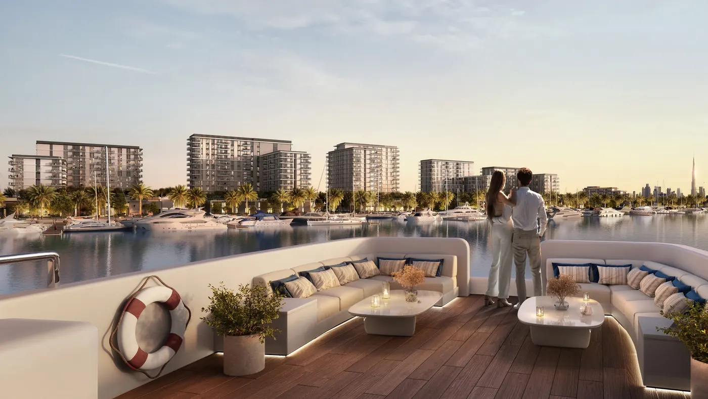 A couple on a yacht deck looking across the marina to the residences